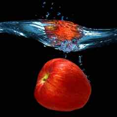 红色的苹果下降了水飞溅孤立的黑色的