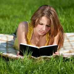 美丽的年轻的女人阅读书户外