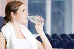 美丽的体育运动女人喝水健身房