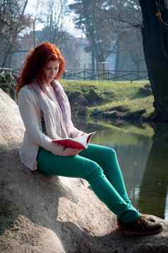 美丽的红色的头年轻的女人阅读书