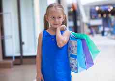 肖像可爱的女孩持有购物袋购物中心
