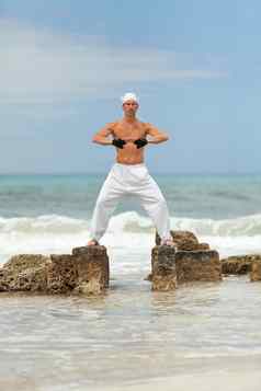 健康的男人。普拉提瑜伽冥想海滩夏天