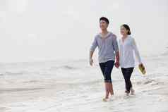 年轻的夫妇走水域边缘海滩中国
