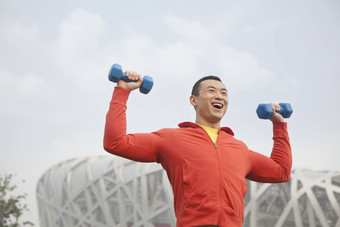 年轻的男人。锻炼哑铃公园北京