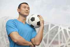 年轻的男人。持有足球球北京
