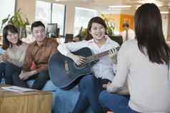 年轻的办公室工人玩吉他的同事们