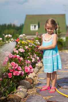 女孩蓝色的衣服浇水花软管花园