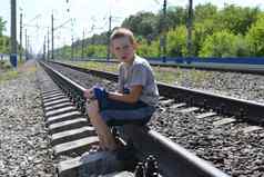 肖像十几岁的男孩坐着Rails