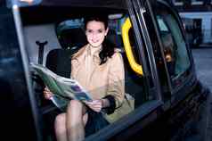 女乘客阅读报纸内部出租车