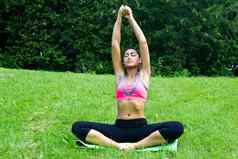 年轻的适合女人实践瑜伽公园冥想放松