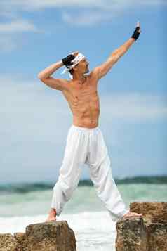 健康的男人。普拉提瑜伽冥想海滩夏天