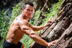 英俊的肌肉发达的shirless登山者攀爬岩石墙