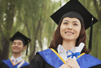 年轻的大学毕业生持有文凭女人前面