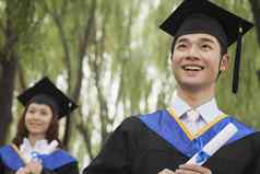 年轻的大学毕业生持有文凭男人。前面