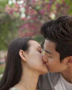 年轻的夫妇爱接吻在户外公园
