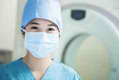 肖像年轻的女外科医生穿外科手术面具操作房间
