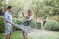 夫妇玩花园软管喷涂花园