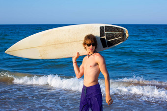 男孩青少年冲浪者快乐钻冲浪板海滩