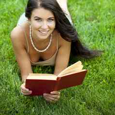 年轻的美丽的年轻的女人阅读书户外