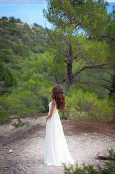 美丽的女孩穿白色飘逸衣服森林