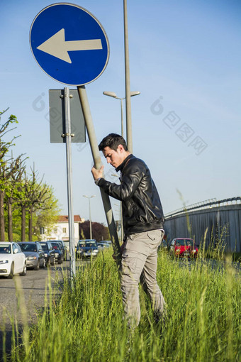 年轻的男人。路标志长路边草