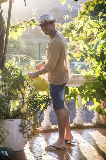 年轻的男人。浇水植物花园