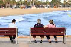 老年人坐着长椅前面海洋海