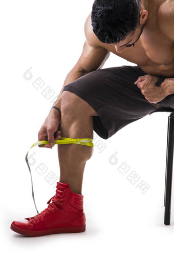 肌肉发达的健美运动员男人。测量小腿磁带测量