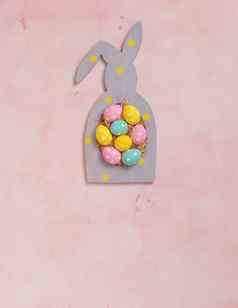色彩斑斓的波尔卡点复活节鸡蛋rabbit-shaped框架粉红色的混凝土背景