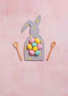 色彩斑斓的波尔卡点复活节鸡蛋rabbit-shaped框架粉红色的混凝土背景