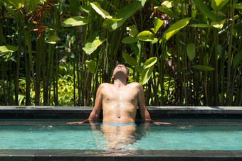 男人。放松户外水疗中心∞游泳池包围郁郁葱葱的热带绿色植物乌布巴厘岛