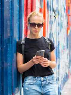 女人智能手机色彩斑斓的涂鸦墙纽约城市美国