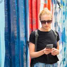 女人智能手机色彩斑斓的涂鸦墙纽约城市美国