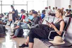 女旅行者细胞电话等待董事会飞机离开盖茨亚洲机场终端