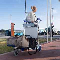年轻的女人运输行李到来停车国际机场离开termainal行李电车