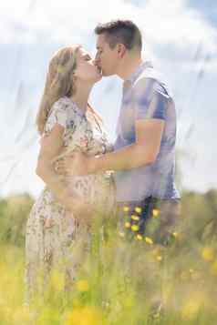 年轻的快乐怀孕了夫妇爱持有手放松草地