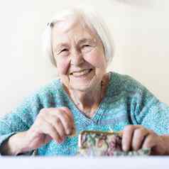快乐的上了年纪的年女人坐着表格首页快乐养老金储蓄钱包支付账单