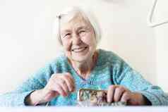 快乐的上了年纪的年女人坐着表格首页快乐养老金储蓄钱包支付账单