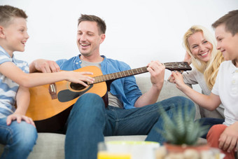 快乐高加索人家庭微笑玩吉他唱歌歌曲舒适的现代首页