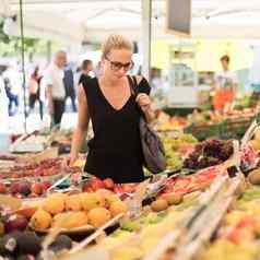 女人购买水果蔬菜当地的食物市场市场摊位各种有机蔬菜