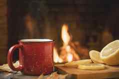 红色的杯子热茶柠檬前面燃烧壁炉安慰温暖炉概念