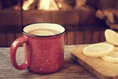 红色的杯子热茶柠檬前面燃烧壁炉安慰温暖炉概念