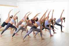 集团年轻的运动有吸引力的人瑜伽工作室练习瑜伽教训教练伸展运动地板上trikonosana三角形瑜伽构成健康的活跃的生活方式工作健身房