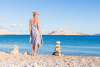 快乐无忧无虑的女人享受晚些时候下午走白色pabbled海滩分页岛克罗地亚