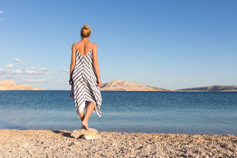 快乐无忧无虑的女人享受晚些时候下午走白色pabbled海滩分页岛克罗地亚