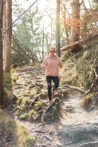 活跃的运动女人听音乐运行秋天秋天森林女跑步者培训户外健康的生活方式图像年轻的高加索人女人慢跑