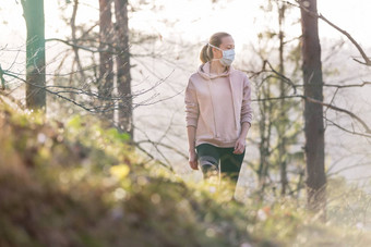 电晕病毒科维德传播世界肖像高加索人运动女人穿医疗保护脸面具走森林电晕病毒