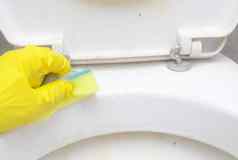 男人。黄色的保护手套洗脏Rim厕所。。。海绵浴室常规的国内清洁