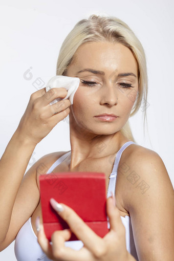 年轻的女人清洁脸湿湿巾镜子手