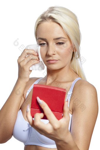年轻的女人清洁脸湿湿巾持有镜子